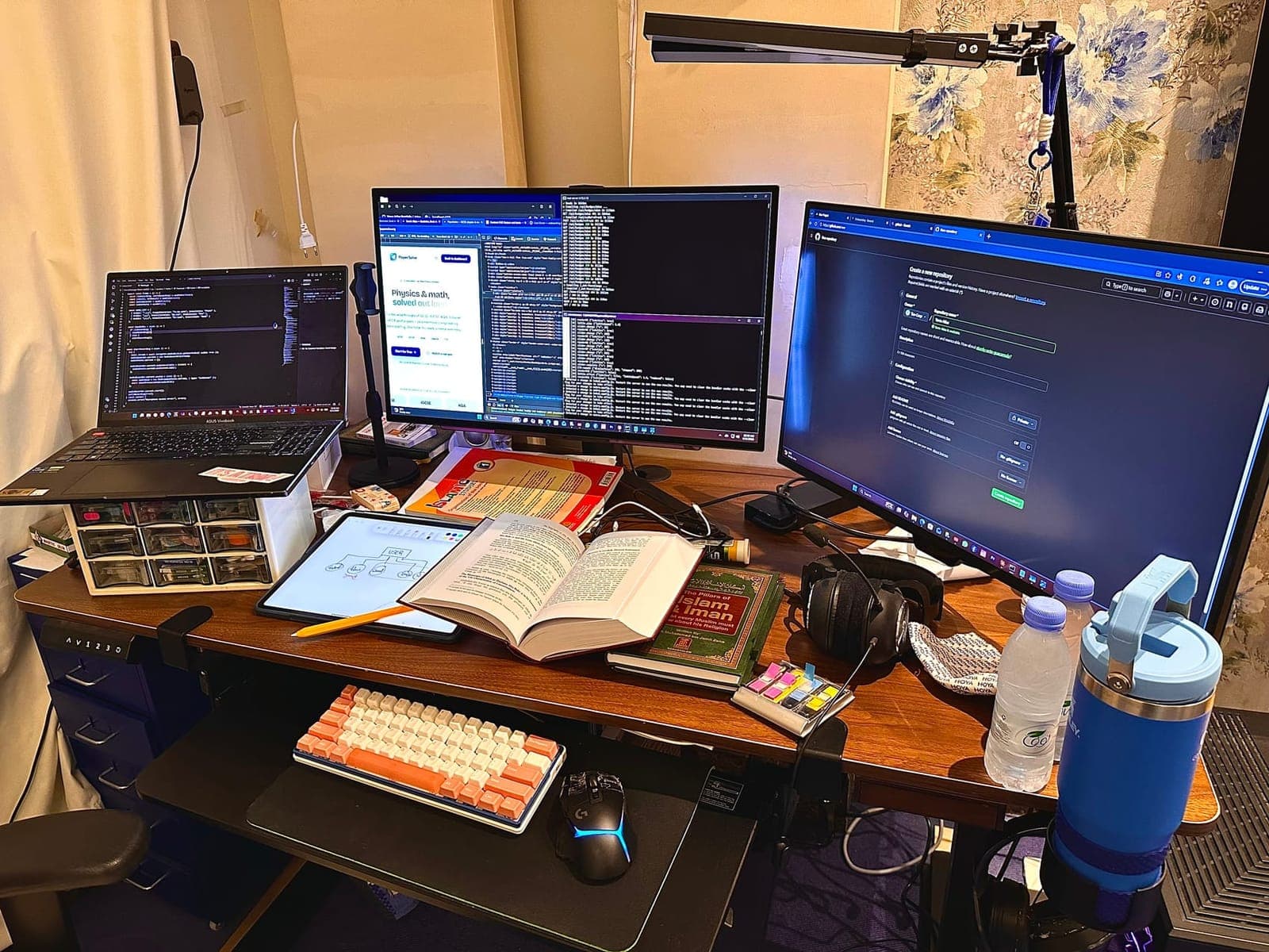 Yarra's workspace in Riyadh — three screens of code, an open Quran and an architecture notebook, her Islamic Studies book, and a mechanical keyboard